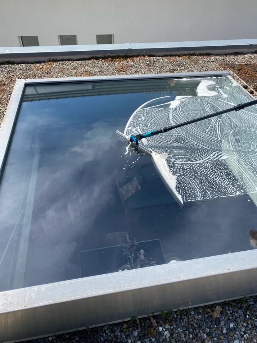 Verrière de toit en cours de nettoyage à la raclette
